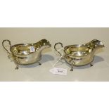 A pair of George V silver sauce boats with scroll handles and gadrooned rims, on scallop shell