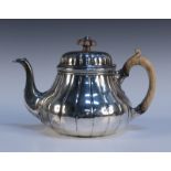 A William IV silver teapot of low bellied form and domed hinge lid with vertical reeded