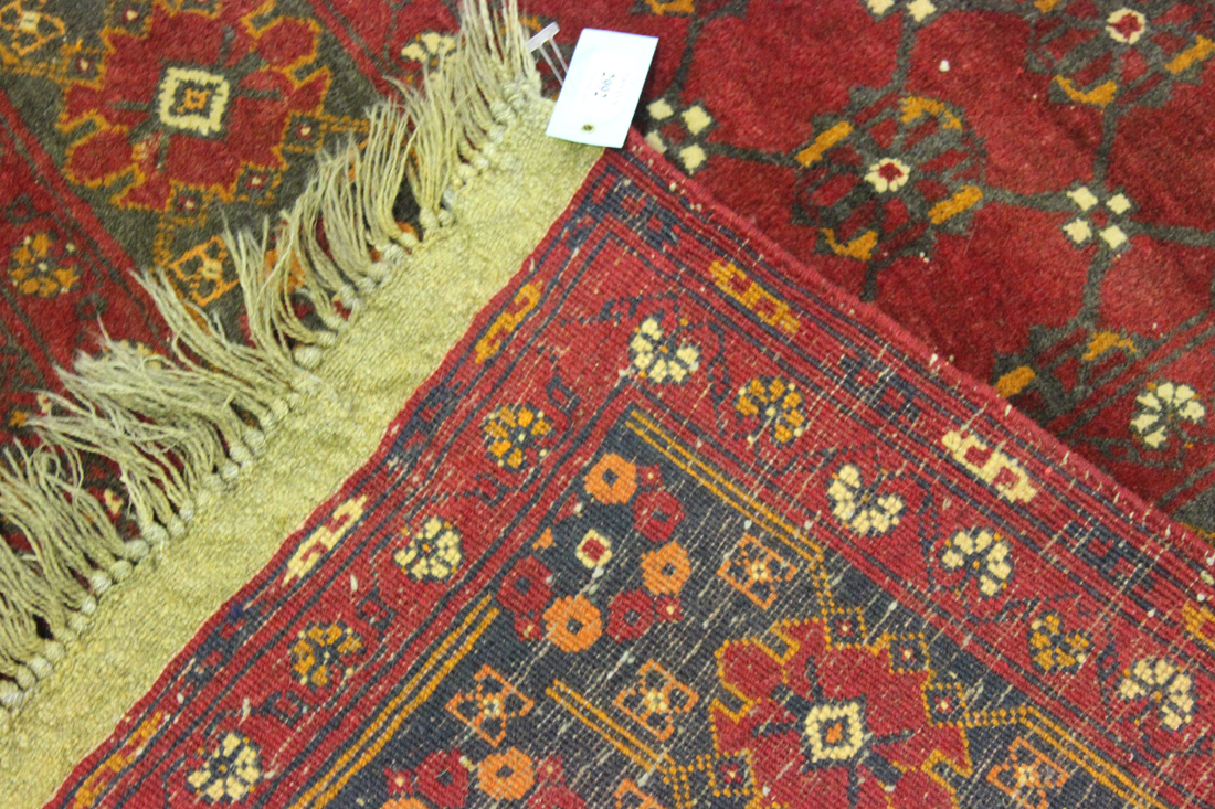 An Afghan carpet, mid/late 20th Century, the claret field with an overall flowerhead lattice, within - Image 2 of 2