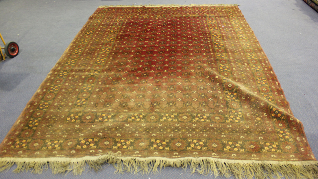 An Afghan carpet, mid/late 20th Century, the claret field with an overall flowerhead lattice, within