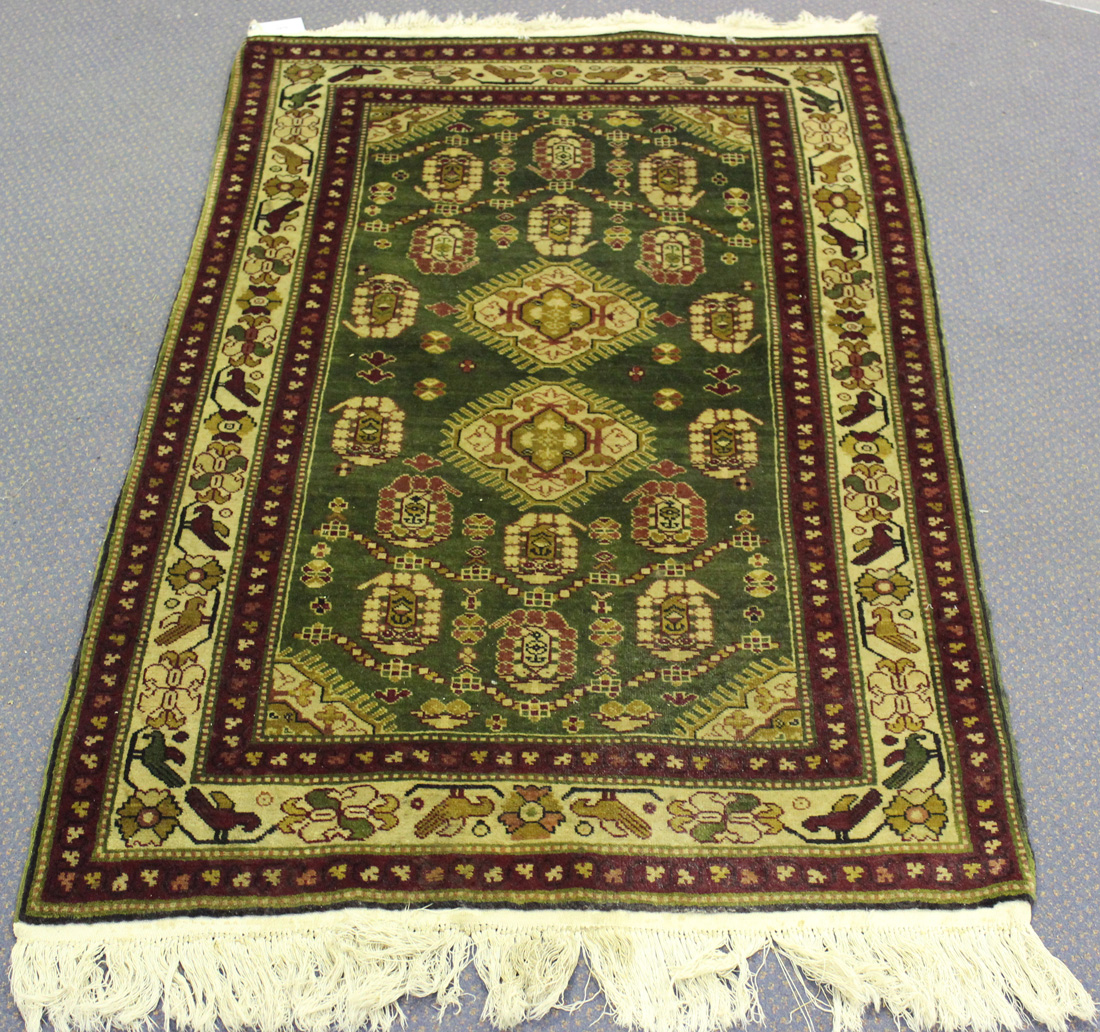 A Persian rug, late 20th Century, the green field with two hooked medallions supported by floral