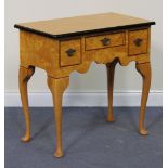 A modern reproduction maple lowboy, the top with an ebonized border above three frieze drawers, on