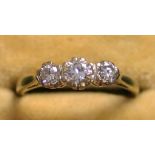 A white gold and diamond three stone ring, claw set with a row of circular cut diamonds, with the