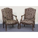 A pair of Louis XV style walnut framed fauteuil armchairs, upholstered in foliate patterned brown