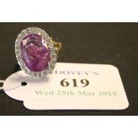 A pink sapphire and diamond oval cluster ring, claw set with the oval cut pink sapphire within a