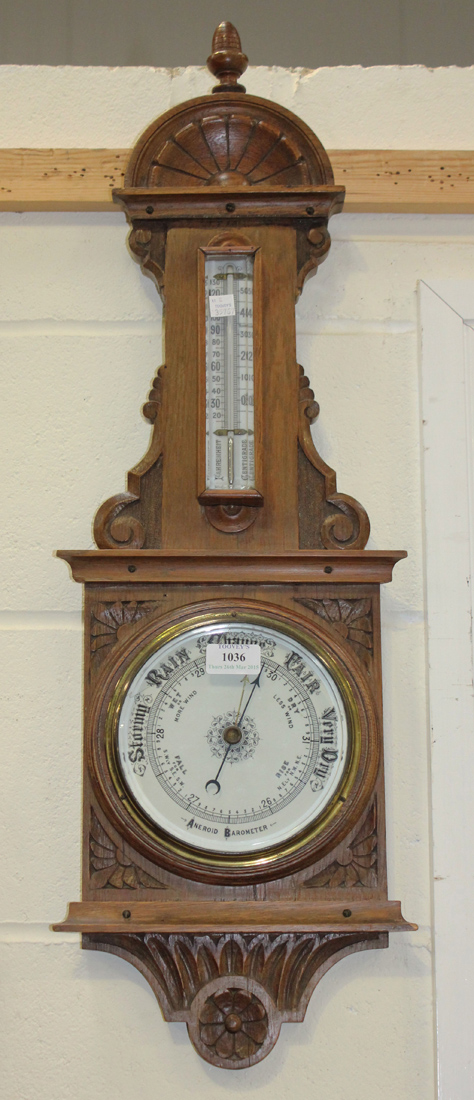 An early 20th Century oak aneroid barometer with ceramic dials and mercury thermometer, the case