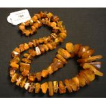 A single row necklace of ninety graduated irregular semi-translucent and opaque rustic treated amber