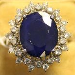 A sapphire and diamond oval cluster ring, claw set with the oval cut sapphire within a pierced