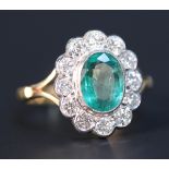 A gold, emerald and diamond oval cluster ring, collet set with the oval cut emerald within a