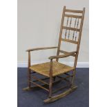 A late 19th Century Shaker style limed ash ladder back rocking chair with a rush seat, on turned