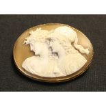A gold mounted oval shell cameo brooch carved as the portraits of two goddesses, Athena and possibly