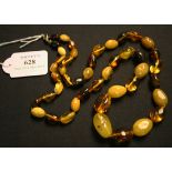 A single row necklace of graduated oval opaque and translucent vari-coloured treated amber beads, on