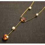 A gold, seed pearl and brown gem pendant necklace, claw set with a circular cut brown zircon to