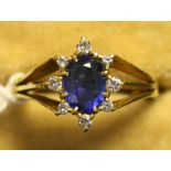 A gold, sapphire and diamond oval cluster ring, claw set with the oval cut sapphire within a