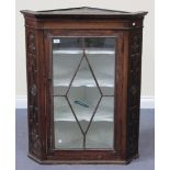 A 19th Century oak hanging corner cabinet with carved decoration, fitted with a single astragal