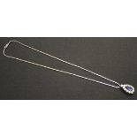 An 18ct white gold, diamond and cabochon sapphire set drop shaped pendant, mounted with the cabochon