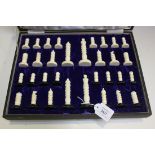 A 1930s ivory chess set with carved decoration, one side with black bases, the other left natural,