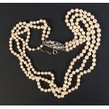 A three row necklace of graduated cultured pearls, on a diamond set oval openwork clasp decorated