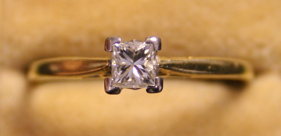 An 18ct gold and diamond single stone ring, claw set with a princess cut diamond.