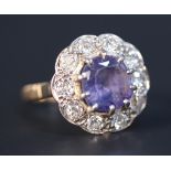 A gold, sapphire and diamond circular cluster ring, claw set with the circular cut blue/lilac