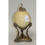 A 19th Century carved ostrich egg with plated mounts and stand, the egg carved in low relief with