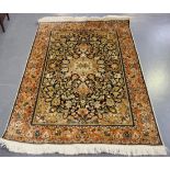 A Kashmir part silk rug, late 20th Century, the charcoal field with a shaped medallion, within an