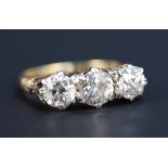 An 18ct gold and diamond three stone ring, claw set with a row of cushion shaped diamonds, with