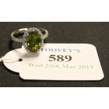 An 18ct white gold, peridot and diamond oval cluster ring, claw set with the oval cut peridot within