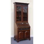 A George V mahogany bureau bookcase cabinet with a blind fretwork frieze above two glazed doors, the