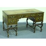 An early 20th Century figured walnut desk, the gadrooned top inset with brown leather above an