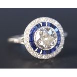 A diamond and sapphire circular cluster ring, collet set with the principal cushion shaped diamond