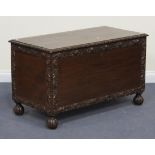 A 20th Century Eastern hardwood trunk, the hinged lid above panelled sides with carved borders, on