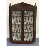 A George III mahogany hanging corner display cabinet with satinwood stringing, the arched pediment