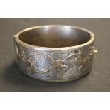 A silver oval hinged bangle, the front with parcel gilt decoration depicting a bird and floral