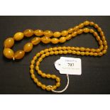 A single row necklace of eighty-two oval graduated semi-translucent honey coloured reconstituted