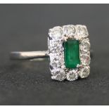 An 18ct white gold, emerald and diamond rectangular cluster ring, claw set with the rectangular step