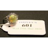 An opal and diamond cluster ring, claw set with the circular cabochon opal within a surround of