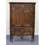 An 18th Century oak corner cupboard, the moulded pediment above four panel doors, on cabriole