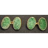 A pair of Chinese gold mounted jade cufflinks, each oval jade panel carved and pierced with foliage,