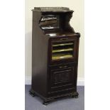 An Edwardian walnut music cabinet, the mirrored gallery back above a glazed door and a single carved