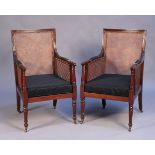 A pair of late Victorian mahogany framed bergère library armchairs with caned seats, backs and arms,