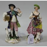 A pair of Continental porcelain figures, 20th Century, modelled as street vendors, the lady