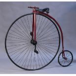 A 20th Century replica of a penny-farthing bicycle with burgundy painted metal frame, leather seat