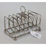 A George III silver six division wirework toast rack with central ring handle, on bun feet, London