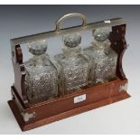 A late Victorian oak three bottle tantalus with nickel plated mounts and lock, width approx 36cm (