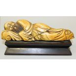 A Chinese carved ivory figure of a sleeping sage, late 19th/early 20th Century, on a stained wood