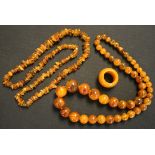 A single row necklace of irregular vari-coloured amber beads, an amber ring and a simulated amber