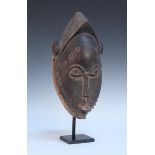 A late 19th/early 20th Century African Baule tribe carved hardwood female mask of elliptical form