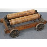 An early 20th Century elm and cast iron trolley, fitted with a pair of wooden rollers above four