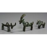 An Islamic green patinated cast bronze pendant in the form of a goat and two similar pendants in the